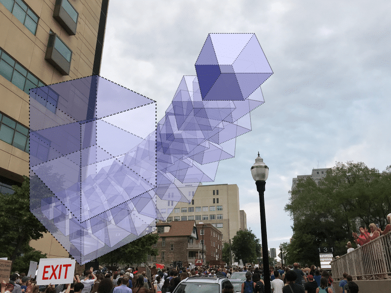A dotted purple cube opens up and a series of smaller purple cubes escape it, over a picture of 2020 protests near the jail in downtown Madison, with the street and sidewalks full of people. A sign reads "EXIT". Illustration by Dan Fitch. Photo by Oona Mackesey-Green.