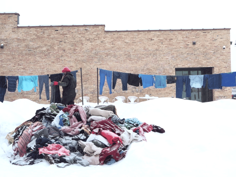 At Garver Feed Mill, artist Ray Carruthers hangs an assortment of blue garments on clotheslines in frigid conditions for the exhibit "Fashion Is Forever." In the foreground, a mound of differently colored balled-up clothing sprawls out in a mound of snow.