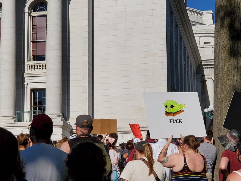 A photo of a June 24, 2022 protest at the Wisconsin Capitol shows a demonstrator holding up a handmade sign depicting Baby Yoda, and underneath it the word "FUCK." Photo by Emily Mills.