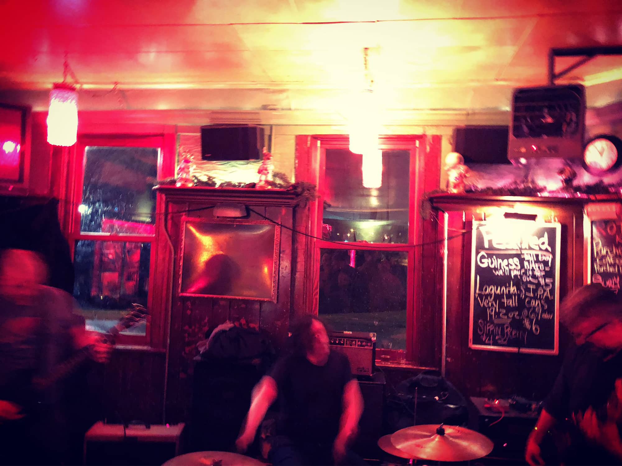 A photo shows the band Czarbles performing at Mickey's Tavern in Madison in 2019. The band members are blurry with motion, and a chalkboard in the background advertises drink specials.