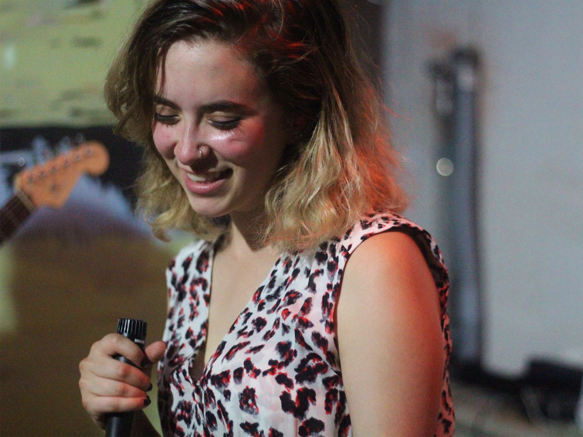 Montana Levy is shown in a leopard-print dress. Her hand is wrapped around a microphone. She is in mid-performance, eyes closed, head tilted down, smiling. Photo by Steven Spoerl.