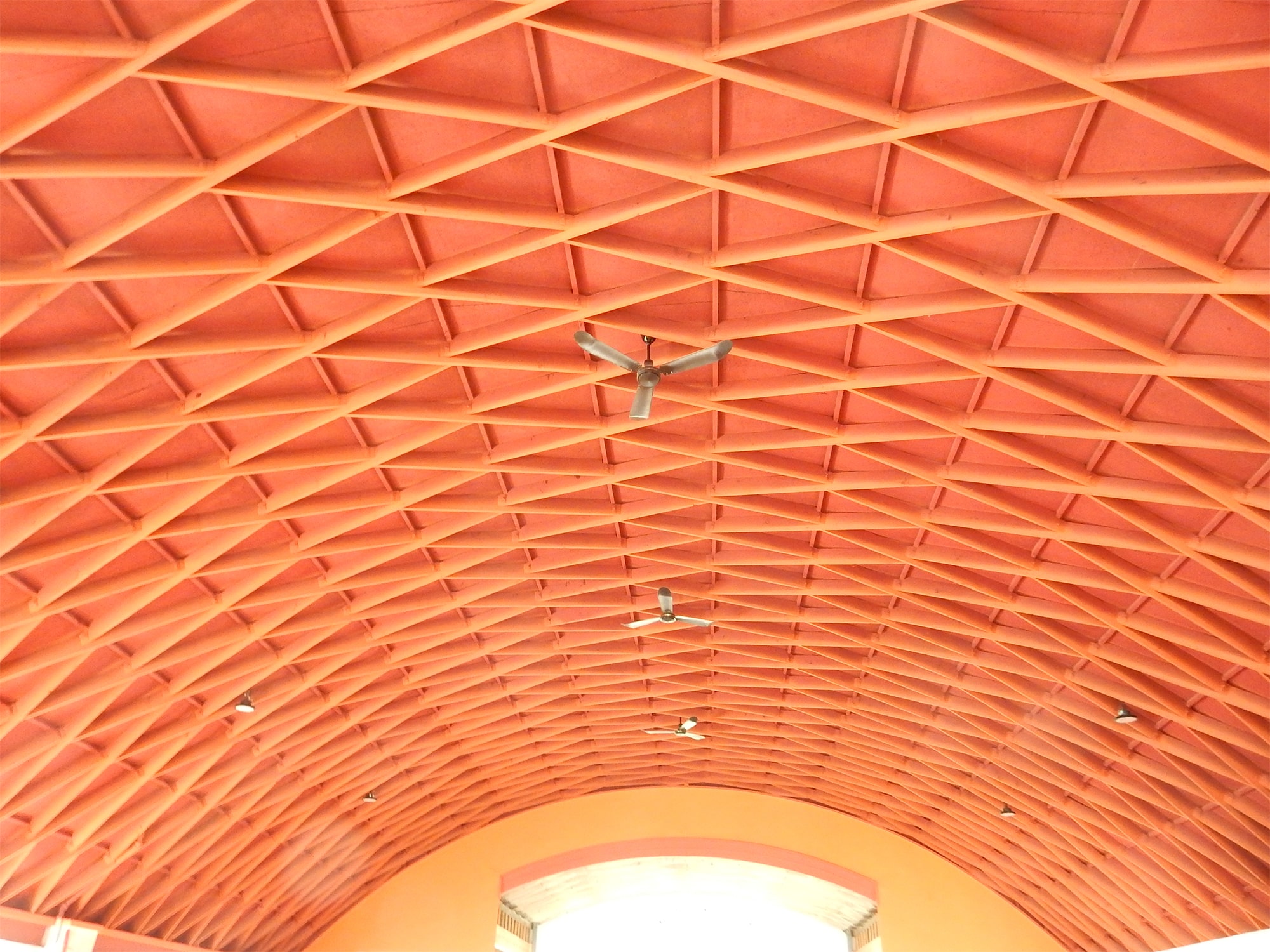 The ceiling of the main room at 1925 Winnebago Street is photographed from the floor level, depicting orange-red beams in an arch structure known as a lamella ceiling.
