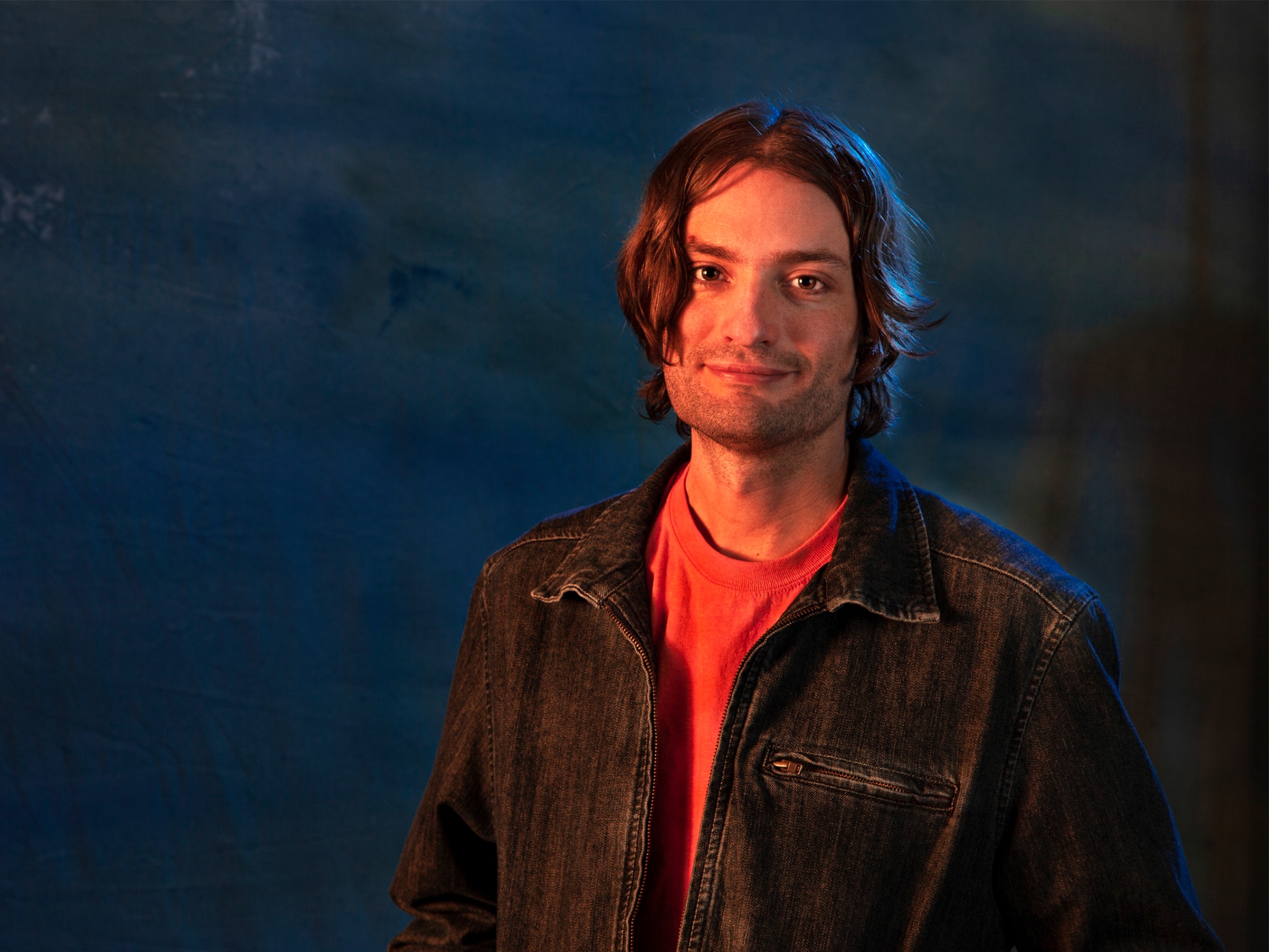 Musician Kyle Rightley is photographed against a blue background, facing the camera.