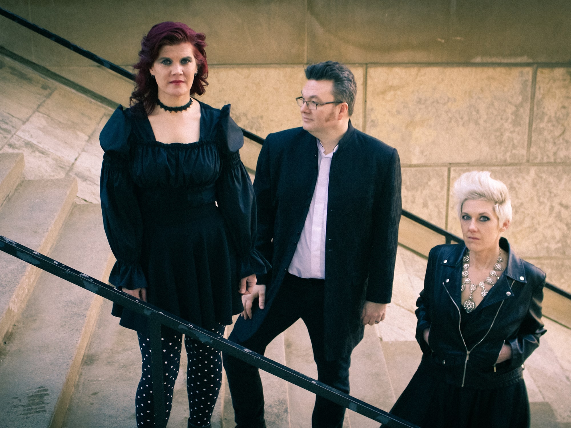 Three members of the band Null Device pose on a staircase for a publicity photo.