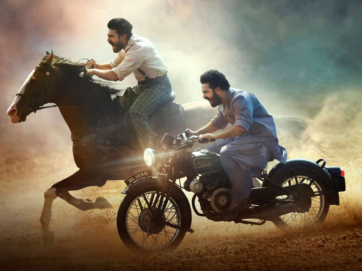 Alluri Sitarama Raju (Ram Charan) rides a horse and Komaran Bheem (N.T. Rama Rao Jr.) rides as motorcycle, speeding through the desert in high spirits.