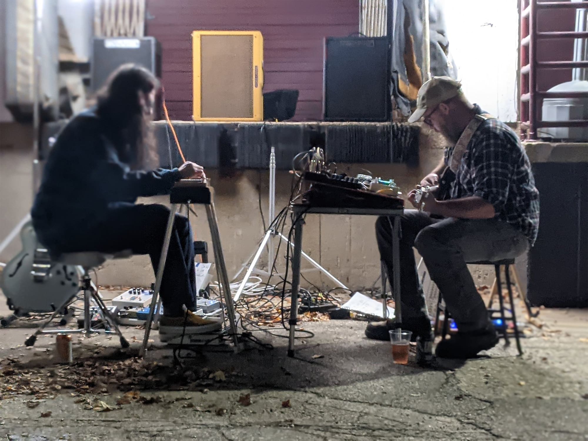 A photo shows the members of music duo Good Corners seated and performing in a warehouse-like setting.