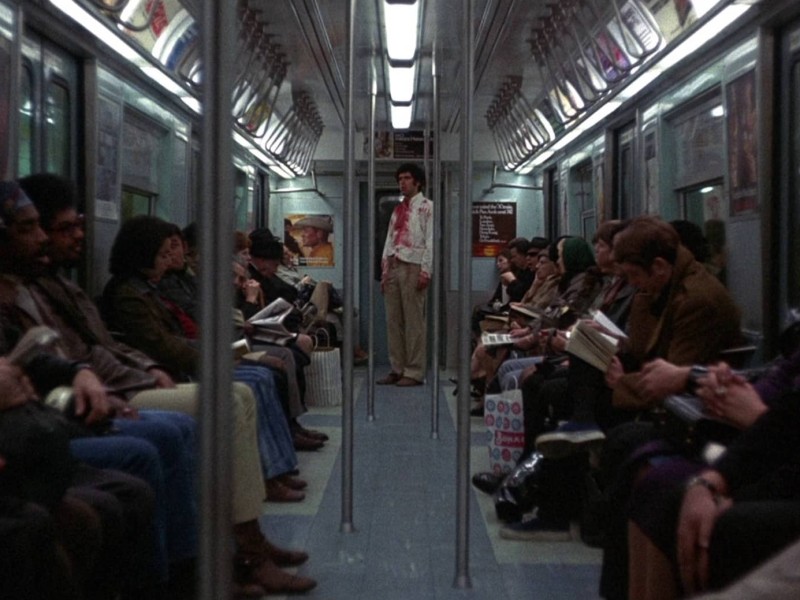 A blood-soaked Alfred Chamberlain (Elliott Gould) stands in the middle of a New York subway car while the other passengers pay no attention to him.