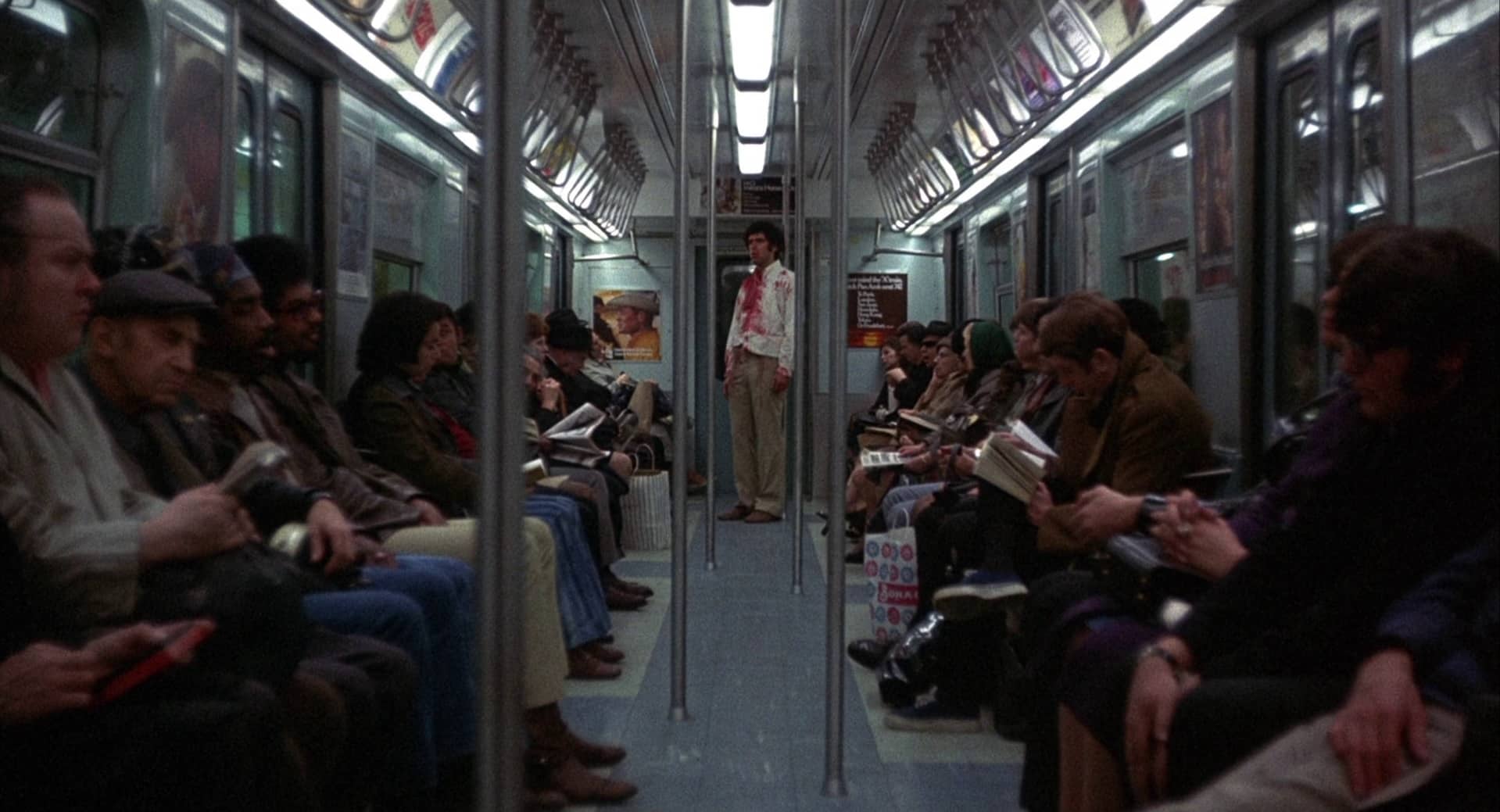 A blood-soaked Alfred Chamberlain (Elliott Gould) stands in the middle of a New York subway car while the other passengers pay no attention to him.