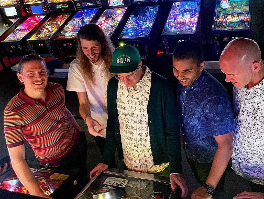In a photo taken by Michael Grittani, Mr. Chair (Mike Koszewski, Jason Kutz, Ben Ferris, José Guzmán, and Mark Hetzler) pose at I/O Arcade Bar pinball machines.