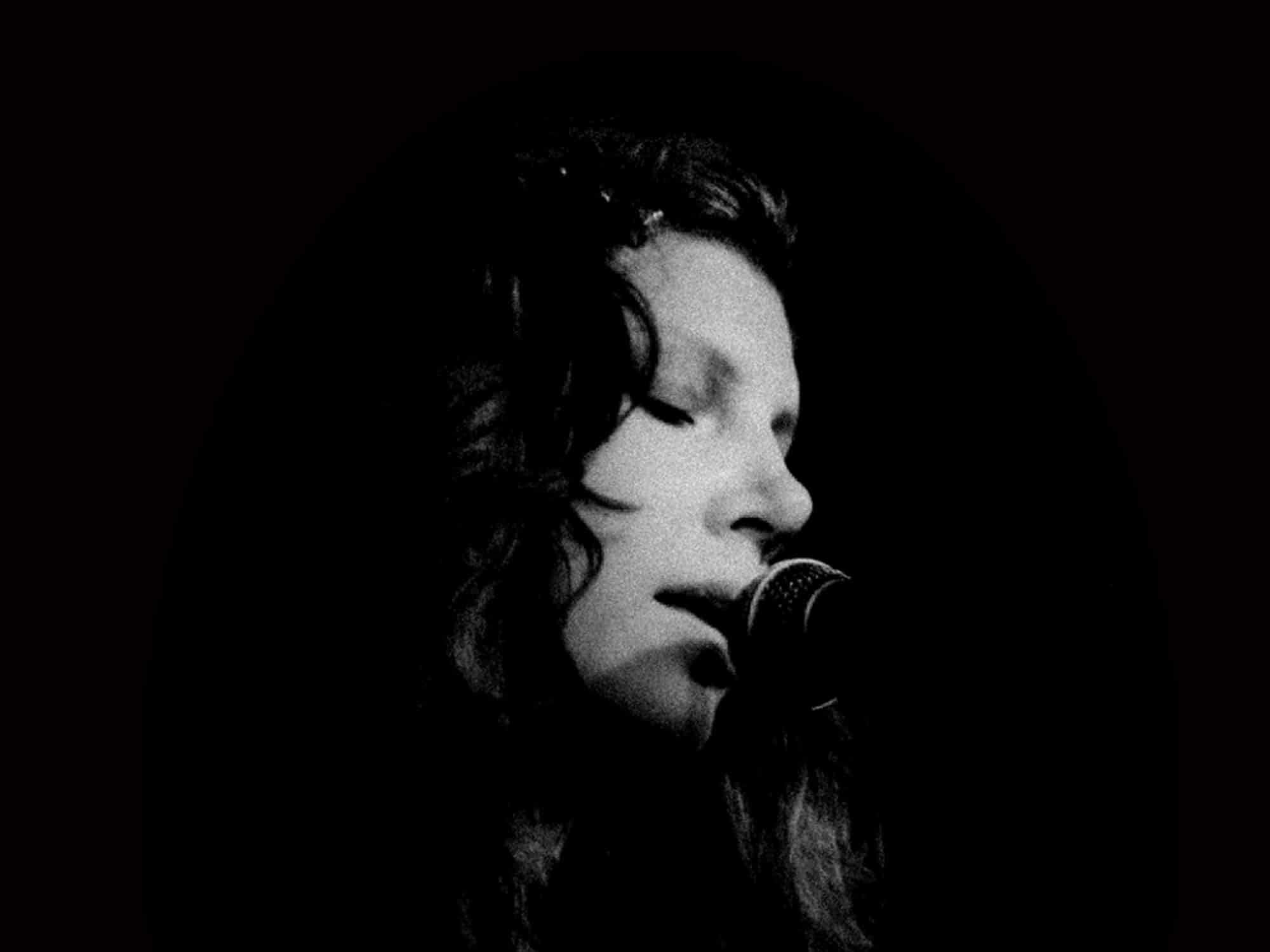 A black-and-white photo shows a close-up of musician Mimi Parker's face.