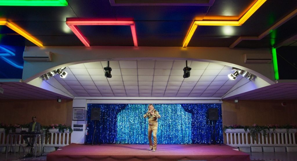 At a long shot from a glitzy stage, singer Richie Bravo (Michael Thomas) leads his dozens of fans in a singalong.