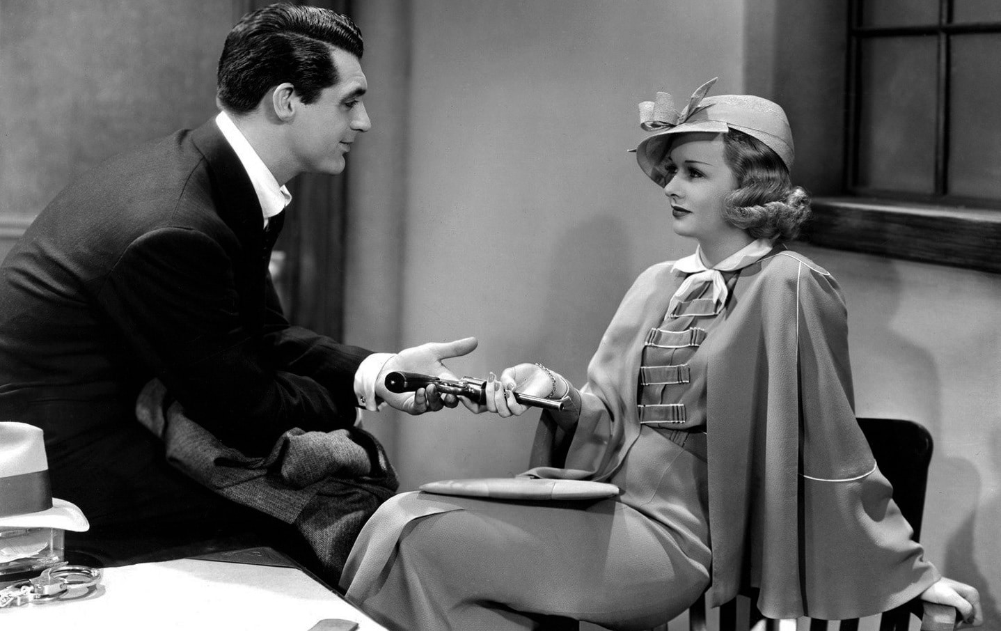 Eve Fallon (Joan Bennett) hands detective Danny Barr (Cary Grant) his gun back. Both coquettishly smile at one another.