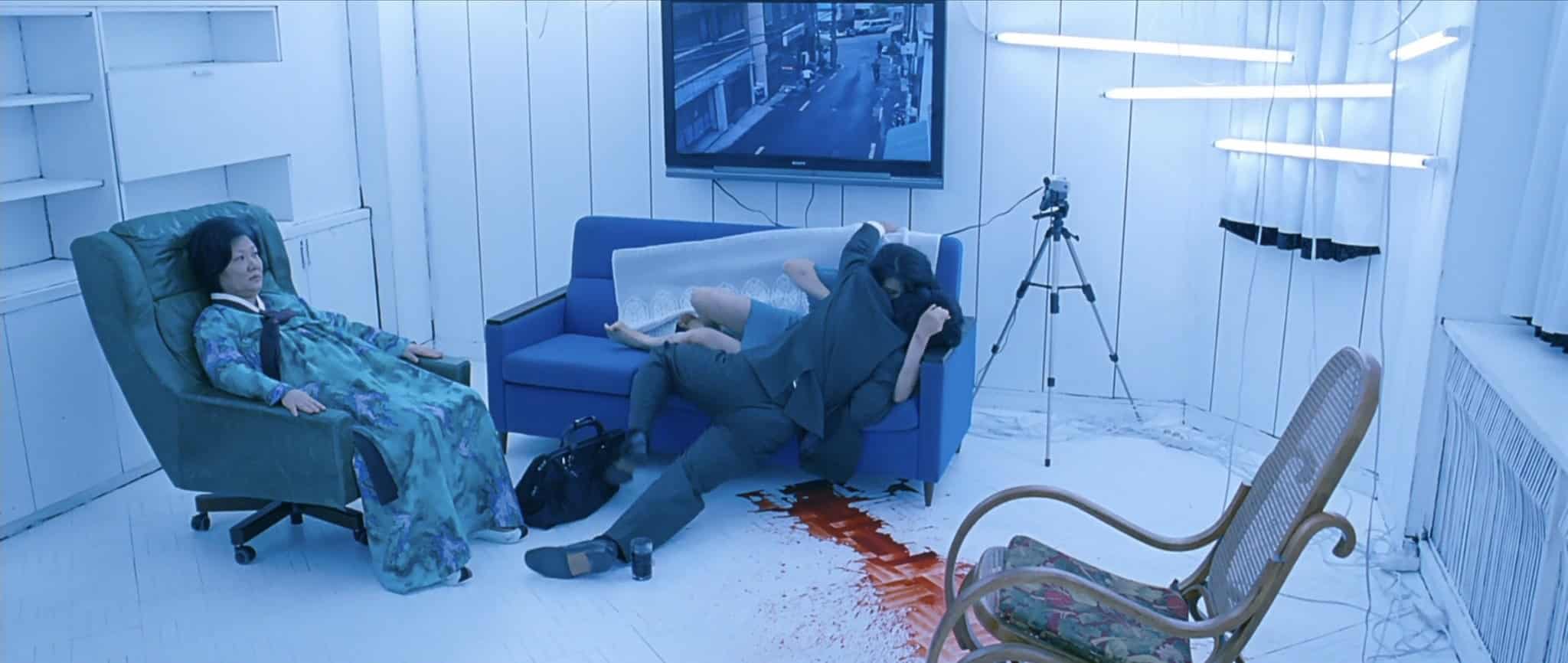 In a white room lit by fluorescent lights, Tae-Ju (Kim Ok-bin) feeds on an unsuspecting victim while her paralyzed mother-in-law (Kim Hae-sook) watches to their left.