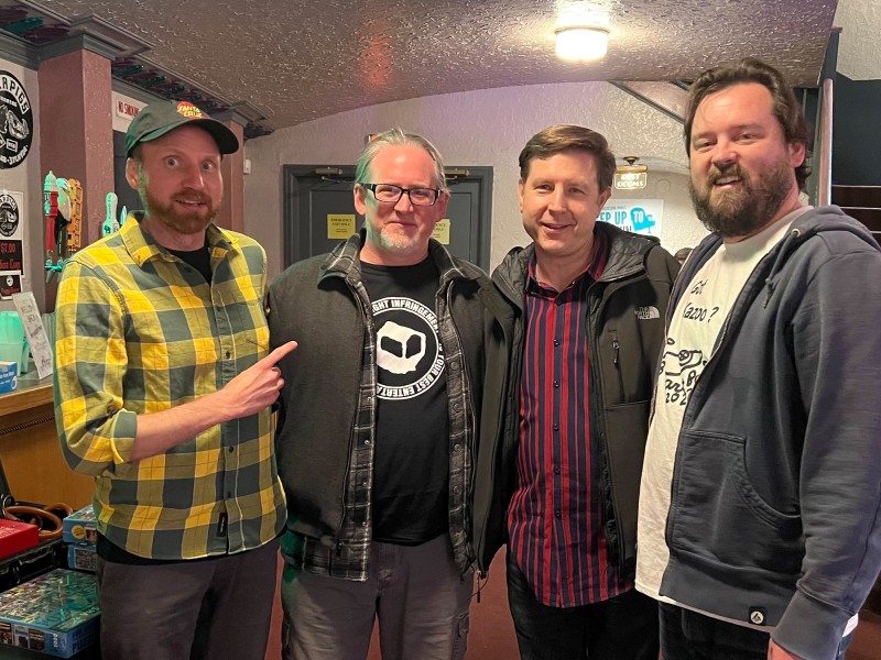The Found Footage Festival's Nick Prueher (far left) and Joe Pickett (far right) posing with Jim's Coins owner Jim Essence (second from right) in the Barrymore Theatre lobby during a FFF event in December 2022. Photo by Harry Charles Loomer-Young.
