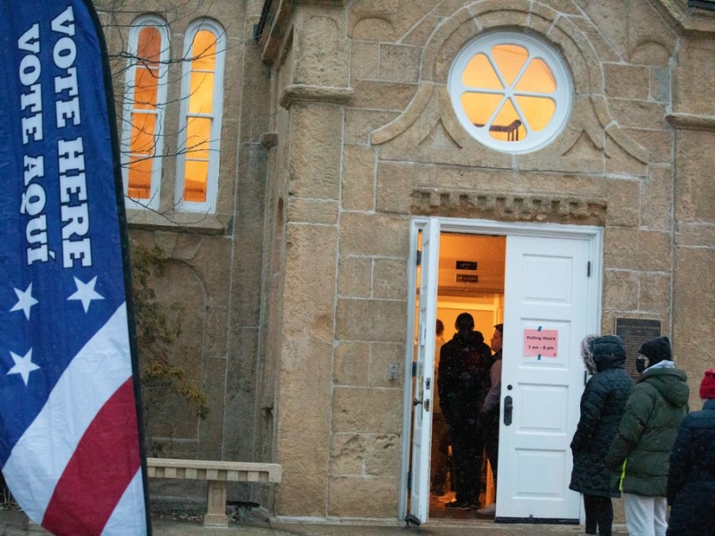 Voters line up outside the Gates of Heaven in Madison with a "Vote Here" sign out front.