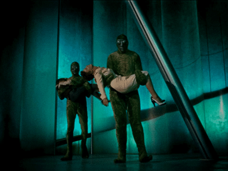 The amphibious-looking Martians cradle an incapacitated David (back left) and Dr. Patricia Blake (center).