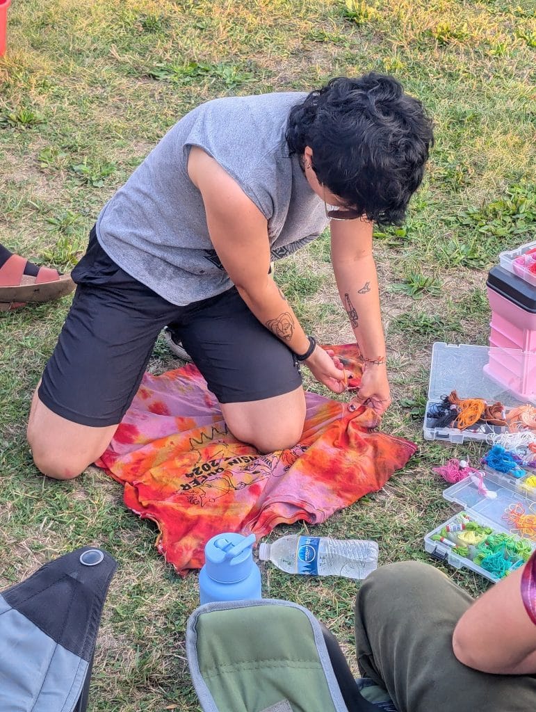 Photo of a person cutting off the sleeves of a tie dyed t-shirt. 