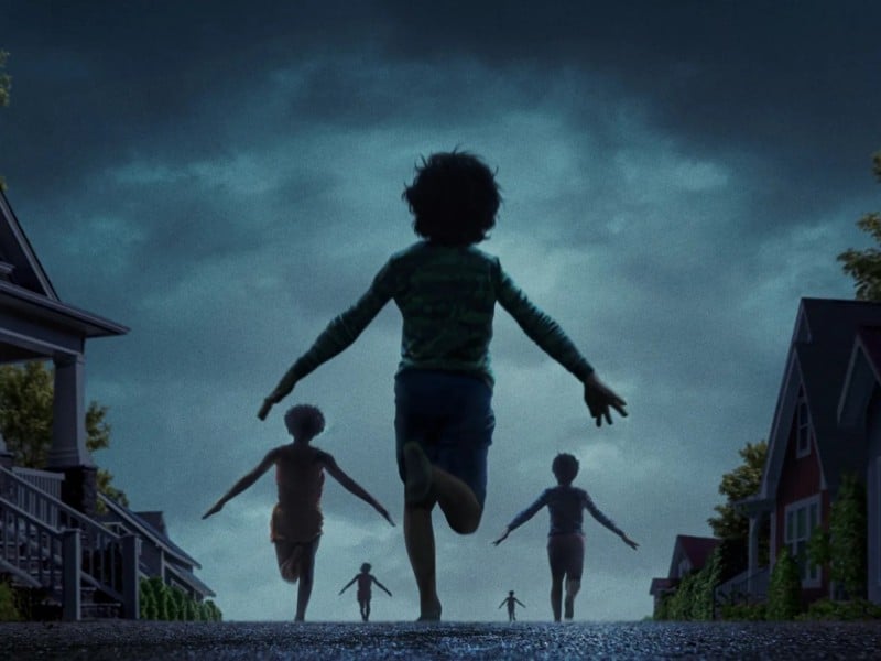 A modified still from the film "Weapons" shows several third-grade children running away from their suburban homes in the dead of night. The color-grading renders everything in a blue-ish grey, with the children running in a strange formation down a street into the distance. The children's arms are all held out to their sides to form an arrow-like shape.