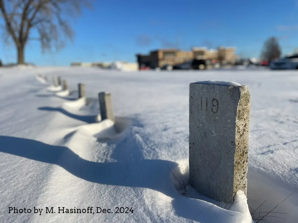Photo of a line of small headstones in the snow.