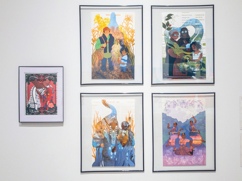 Five printed digital illustrations hang from a gallery wall. The four larger illustrations hanging as a quadrant to the right of center explore themes of water, while the singular piece on the left shows handing embracing holding a keffiyeh and kokum scarf.