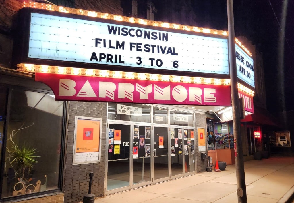 Slightly angled photo at night of the bright, fluorescent-lit marquee at the Barrymore Theatre on Atwood Avenue in Madison, Wisconsin. It reads "Wisconsin Film Festival April 3 to 6" in black lettering on the long illuminated sign.