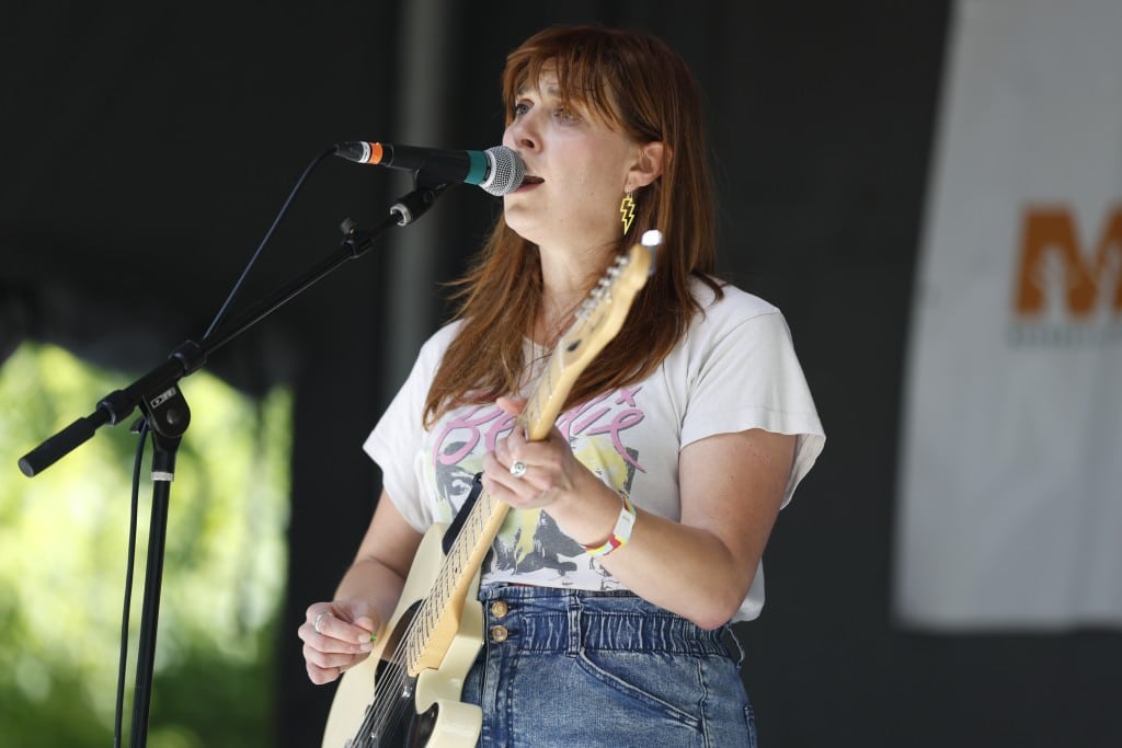 Heavy Looks guitarist-vocalist Rosalind Greiert is playing guitar and singing while looking out past a festival crowd on a sunny summer day.